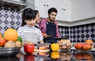 asiatiska familjer lagar mat och föräldrar lär sina döttrar att laga mat i köket hemma. familjeaktiviteter på semester och glad i rekreation koncept foto