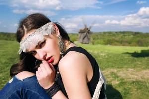 ung vacker flicka med långt mörkt hår i grönt fält i utomhus etnisk by i Kiev Ukraina foto