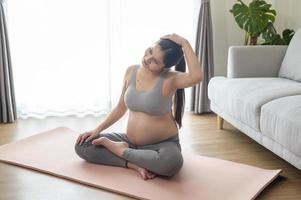 ung gravid kvinna gör yoga hemma, sjukvård och graviditetsvård koncept foto