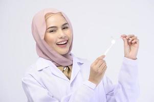 muslimsk kvinnlig tandläkare håller invisalign hängslen över vit bakgrund studio, tandvård och ortodontisk koncept. foto