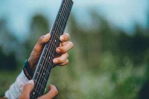 mannens hand spelar akustisk gitarr, spelar gitarr i trädgården ensam, glatt och älskar musiken. foto