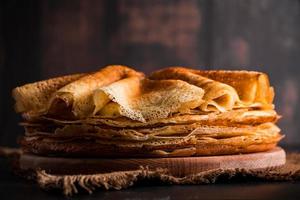 traditionell rysk mat - tunna pannkakor. en bunt crepes på en mörkbrun träbakgrund. foto