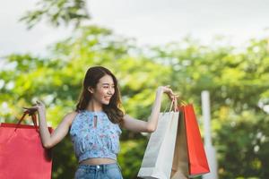 Asiatisk ung leende kvinna njuta av shopping med röd väska. foto