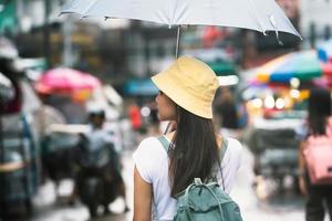 ensam asiatisk resenär kvinna med paraply bland regn foto