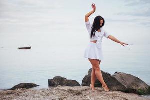 flicka i klänning dansar barfota på sandstrand händer foto