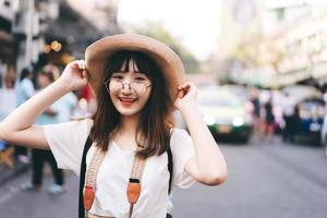glad asiatisk ung glasögon kvinna resenär på marknaden. foto