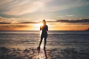 bakifrån av unga vuxna resor asiatisk kvinna koppla av i naturen på stranden havet med morgonhimlen foto