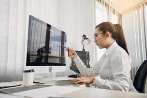 kvinnliga asiatiska mjukvaruutvecklare analyserar tillsammans om koden som skrivits in i programmet på datorn i kontorsrummet. foto