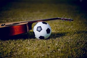 gitarr och fotboll är placerade i gröna gräsmattor. musik och sportidéer och det finns ett kopieringsutrymme. foto