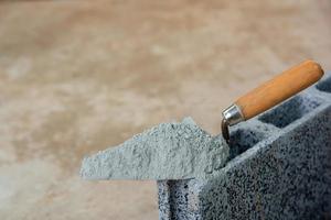 cementpulver eller murbruk med murslev läggs på betongstenen för byggnadsarbete. foto