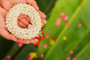 mammas hand som håller en jasmingirland under songkran-festivalen foto