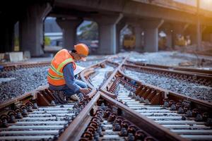 ingenjör järnväg under kontroll byggprocess tågprovning och kontroll av järnvägsarbete på järnvägsstation med radiokommunikation .ingenjör bär skyddsuniform och skyddshjälm i arbetet. foto