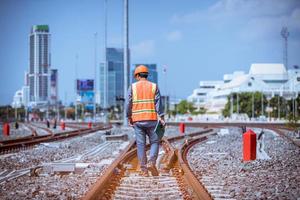 ingenjör järnväg under kontroll byggprocess tågprovning och kontroll av järnvägsarbete på järnvägsstation med radiokommunikation .ingenjör bär skyddsuniform och skyddshjälm i arbetet. foto