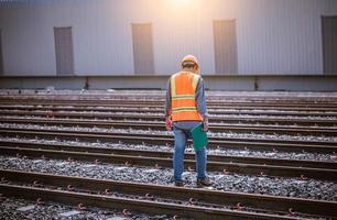 ingenjör järnväg under kontroll byggprocess tågprovning och kontroll av järnvägsarbete på järnvägsstation med radiokommunikation .ingenjör bär skyddsuniform och skyddshjälm i arbetet. foto