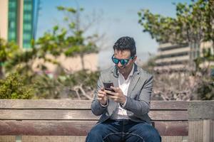 glad affärsman läser meddelande på smartphone på gatan foto
