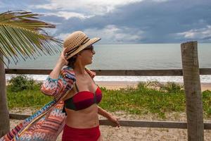 dam i badkläder lutad mot ett trästaket nära stranden i caraiva bahia, Brasilien foto