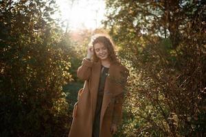 vacker elegant kvinna som står i en park på hösten foto