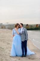 bröllop fotosession av ett par på stranden. blå bröllopsklänning på bruden. foto