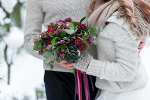 bröllopsbukett med röda och crimson blommor på suddig brud och brudgum bakgrund. vinterbröllop utomhus. närbild. foto