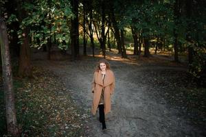 vacker elegant kvinna som står i en park på hösten foto