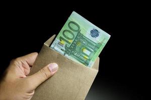 manlig hand som håller lönekuvert europengar sedlar. foto