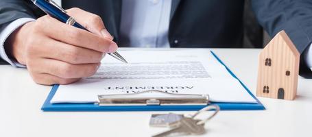 man undertecknar hem kontraktshandlingar. avtalsavtal, fastigheter, köp och försäljning samt försäkringskoncept foto