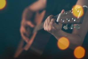 närbild killens hand spelar gitarr. foto