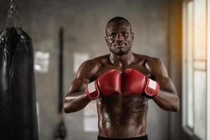 afrikansk man tränar på gym och knytnävar hans boxningsväska knytnävar. sport man träning på gym, fitness, boxning, framgång, träning och kraft foto