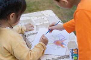sött litet barn målar med färgglada färger. asiatisk flicka med pensel ritning color.baby aktivitet livsstilskoncept foto