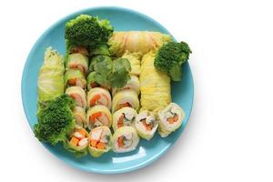 grönsaksrulle, malet fläsk, krabba pinne, kyckling med broccoli i blå platta isolerad på vit bakgrund med urklippsbana. salladsrullar. ovanifrån av hälsosam mat. foto