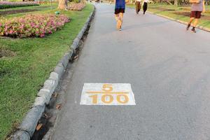 ord 5 delar av 100 symbol skriven på asfaltvägen med suddiga människor som joggar i den offentliga parken. foto