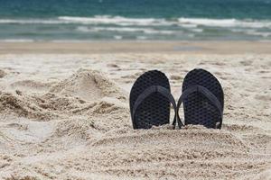 flip flops på stranden. tofflor inbäddade i sandstrand. foto