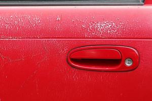 gammal röd dörrhandtagsbil. väderinducerade variationer på bildörren. foto