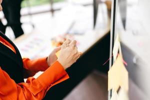 vuxen affärskvinna använder en papperslapp för sticka på en glasbräda på kontoret foto