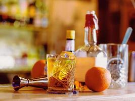 gammaldags cocktail, apelsin, flaskor och bägare på bardisken foto