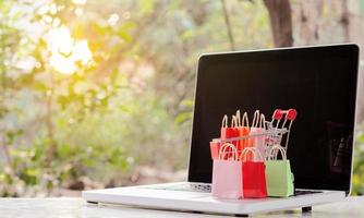 handla online. påsar med en kundvagn logotyp i en vagn på laptop tangentbord. shoppingtjänst på nätet. erbjuder hemleverans foto