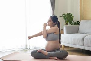 ung gravid kvinna gör yoga hemma, sjukvård och graviditetsvård koncept foto