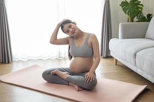 ung gravid kvinna gör yoga hemma, sjukvård och graviditetsvård koncept foto