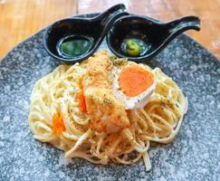 krämig spaghettipasta med räktempura och saltat ankägg serverad med wasabi shoyusås. foto