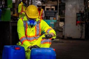 ingenjörsindustrin bär säkerhetsuniform, svarta handskar, gasmask känner sig kvävd när man kontrollerar kemikalietanken i industrins fabriksarbete. foto