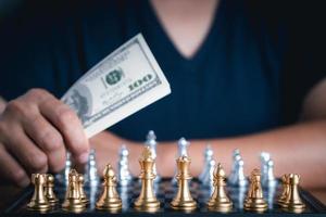 närbild av en ung man hand som håller dollarvaluta som spelar schack foto