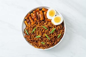 jjajang rabokki - koreanska snabbnudlar eller ramyeon med koreansk riskaka eller tteokbokki och ägg i svart bönsås foto