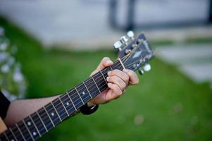 bild av en gitarrist, en ung man som spelar gitarr medan han sitter i en naturlig trädgård, musikkoncept foto