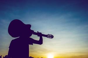 silhuett av en gitarrist i skuggorna vid solnedgången ljus, siluett koncept. foto
