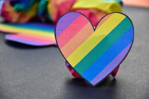två hjärtan gjorda av regnbågsfärgat papper håller i händerna på hbt-personen, koncept för hbtq-gemenskapernas firande i pride-månaden runt om i världen foto