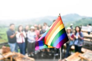 regnbågsflagga, en symbol för hbt-gemenskapen, vinkar i vinden med oskärpa asiatiska studenter i bakgrunden för morgonaktiviteter. koncept för att stödja och driva kampanj för hbt-samhällen i skolan foto