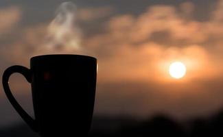 kaffekopp med solnedgången i bakgrunden foto