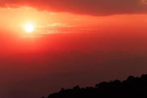 himmelröd färg med solnedgång över bergen foto