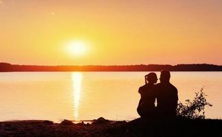romantiska par på stranden vid färgglad solnedgång bakgrund foto