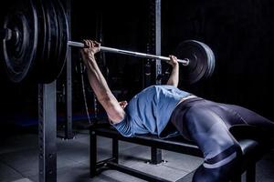 atletisk man i gymmet tränar på skivstångsbänkpressen. foto